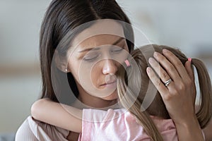 Upset loving mother embracing, comforting little daughter close up photo