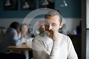 Upset male outcast feel lonely sitting alone in cafe