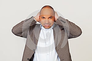 Upset man African American businessman in a jacket, covering his ears with hands, hearing the annoying sound, he has a