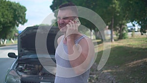 Upset man calls in car service after his car broke down on a rural road. Anxious man talking on the phone.