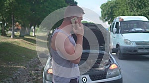 Upset man calls in car service after his car broke down on a rural road. Anxious man talking on the phone.