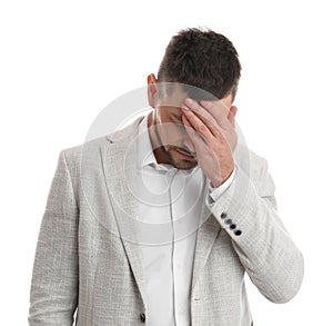 Upset man covering face with hand on white background