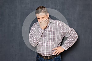 Upset man is covering mouth while suffering and being desperate
