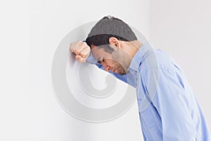 Upset man leaning his head against a wall