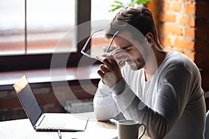 Upset man massaging nose bridge, taking off glasses, feeling eye strain photo