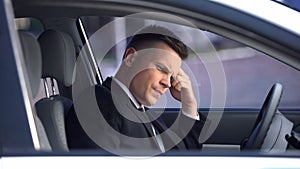 Upset man sitting in car, thinking over problems, stressful life, overwork