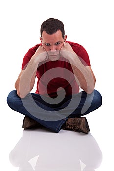 Upset man sitting cross-legged on the floor