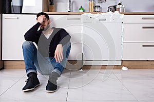 Upset Man Sitting Next To Dishwasher