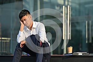 Upset man sitting on stairs outside office building, lost job due financial crisis employee