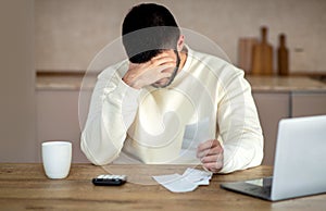 Upset Man Sitting at Table With Head in Hands