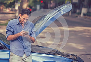 Upset man texting roadside assistance after breaking down