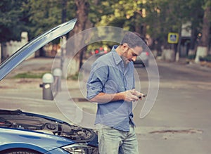 Upset man texting roadside assistance after breaking down