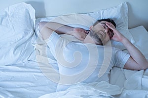 Upset man trying to sleep in his bed at night