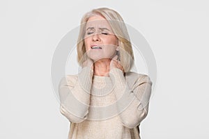 Upset mature woman massage feeling neck pain isolated on background photo