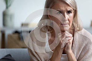 Upset mature woman sitting alone, thinking, feeling unwell photo