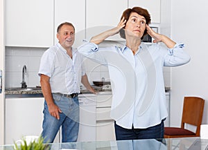 Upset mature woman standing after qurrel with husband at home