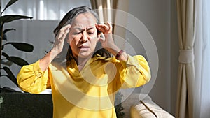 Upset mature woman touching her head suffering from head ache, migraine or dizziness. Age, medicine, health care and