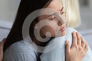 Upset mom and adult daughter hug showing support and care