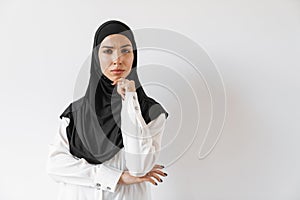 An upset muslim woman in hijab thinking about something and wrinkling her forehead in the white studio photo