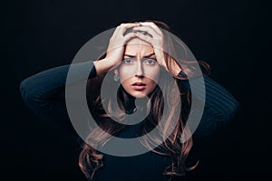 Upset offended beautiful woman holding her hands on head isolated on black background