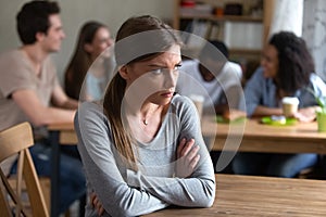 Upset offended by friends young woman sitting alone.