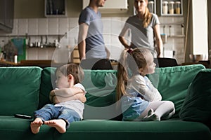 Upset offended brother and sister sitting on couch