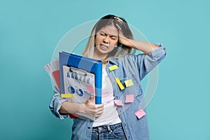 Upset office worker with a lot of work on hand trying to get everything done on time. She is holding a folder of documents