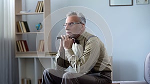 Upset old man leaning on walking stick, taking nap at midday, feeling lonely