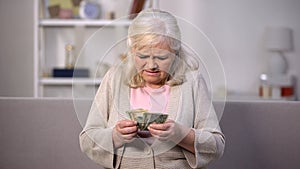 Upset old woman counting dollars, low living standard, pension age increase