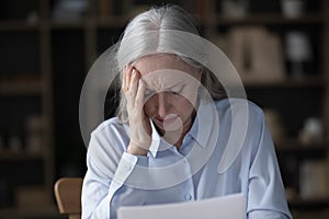 Upset older businesswoman read unpleasant news in letter