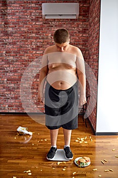 Upset overweight boy after weighing. Teenage kid need to lose some excess weight.