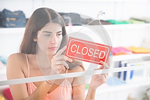 Upset Owner Holding Closed Sign In Clothing Store