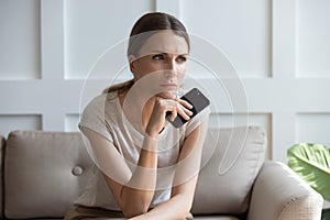 Upset pensive woman holding phone, waiting for call, feeling lonely