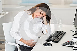 Upset Pregnant Woman Sitting At Computer Desk