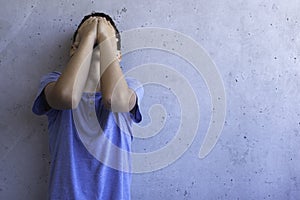 Upset sad boy stand alone and leaning on gray wall. Learning difficulties, family problems, bullying, depression, stress