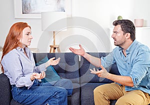 Upset and sad couple arguing with each other on sofa