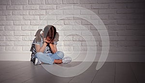 Upset sad sad child girl in stress cries at an empty dark wall photo