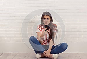 Upset sad skeptical unhappy serious woman talking texting on mobile phone displeased with conversation. Sitting cross-legged.