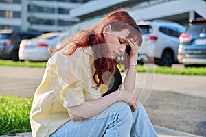 Upset sad unhappy young female sitting outdoor on steps