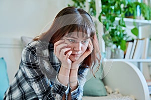 Upset sad young female sitting on couch at home