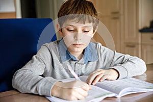 Upset school kid boy making homework during quarantine time from corona pandemic disease. Crying and sad boy frustrating