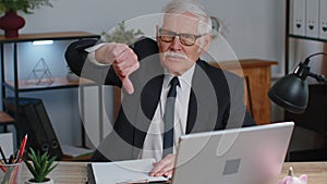 Upset senior business man showing thumbs down sign gesture, disapproval, dissatisfied, dislike
