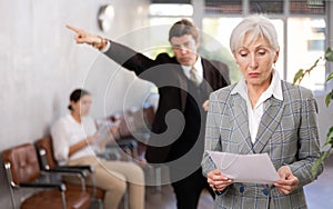 Upset senior businesswoman with displeased boss pointing at door