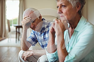 Upset senior couple relaxing on sofa