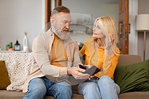 Upset Senior Husband Showing Empty Wallet To Wife At Home