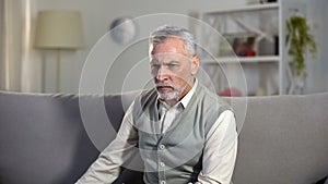 Upset senior male sitting alone in hospice, thinking about life problems, aging