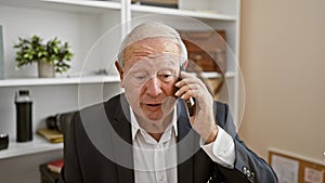 Upset senior man boss arguing over the phone, looking serious in office