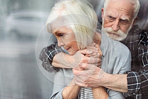 Upset senior man hugging wife, sick