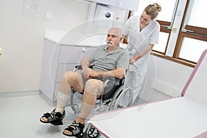 upset senior on wheelchair with nurse standing behind