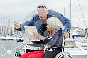upset senior woman in wheelchair being pushed by husband